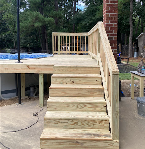 Pressure-treated pool deck with wide stairs and railing beside a brick chimney