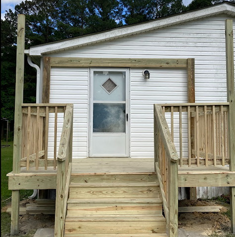 Front entry deck with double railings and steps leading to a white home